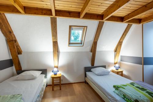 two beds in a room with wooden ceilings at Gite Les Marmottes in Trémouille