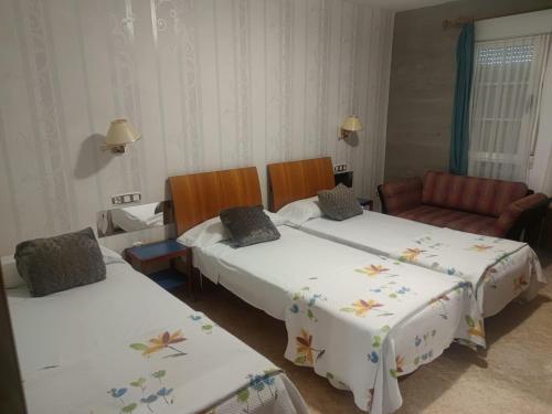 um quarto de hotel com duas camas e um sofá em Hostal Burbia em Villafranca del Bierzo