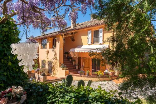 una grande casa gialla con alberi e piante di B&B Glicine ad Ancona