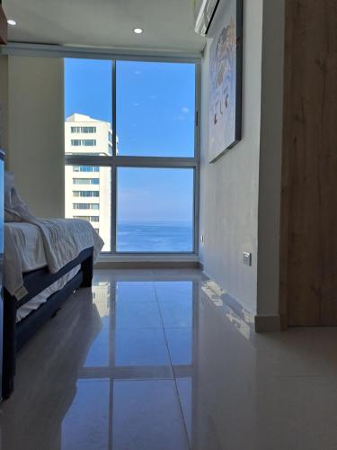 Habitación con cama y ventana grande. en Apartamento frente al mar Rodadero Santa Marta en Santa Marta