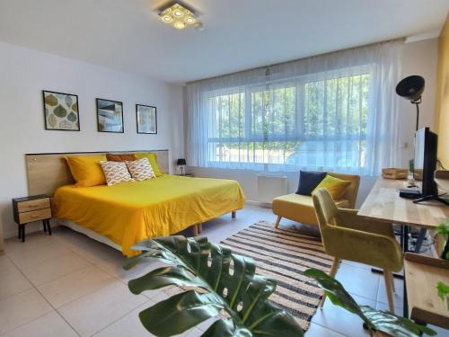 een slaapkamer met een bed en een gele sprei bij Studio LE JUNGLE - ROISSY CDG - Parc Astérix - PARIS in Moussy-le-Neuf