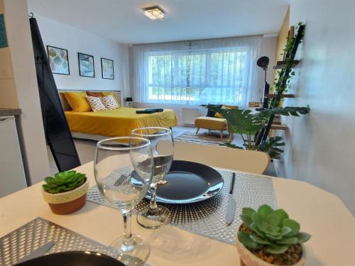 une table à manger avec deux verres à vin et un canapé jaune dans l'établissement Studio LE JUNGLE - ROISSY CDG - Parc Astérix - PARIS, à Moussy-le-Neuf