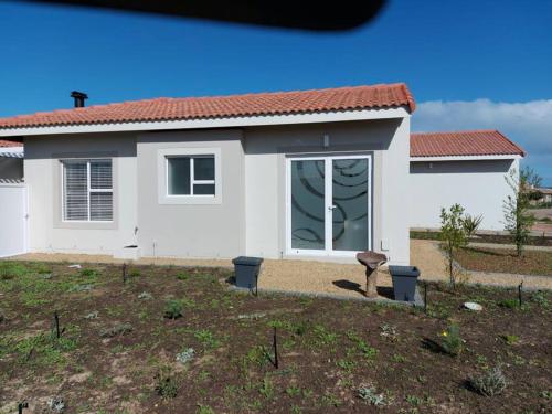 a white house with a window in a yard at One Bedroom Unit with Kitchenette in Langebaan Country Estate - Solar Power in Langebaan