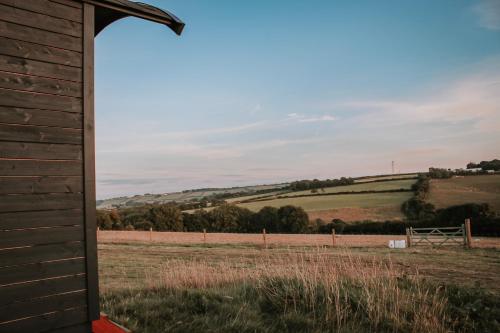 a view of a field from the side of a barn at Stunning Shepherd's Hut Retreat North Devon in Bideford