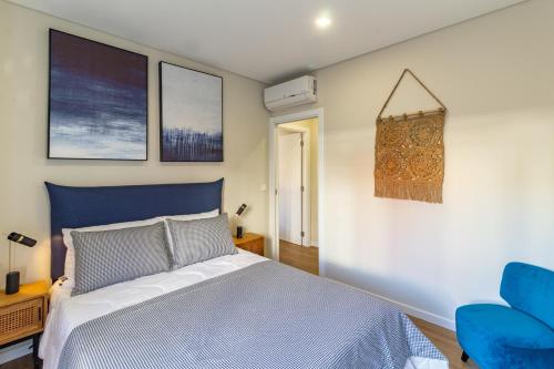 um quarto com uma cama azul e uma cadeira azul em Porta 25 Guesthouse na Covilhã