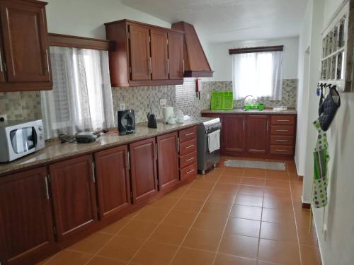 a kitchen with wooden cabinets and a tile floor at Casa do Lajedo in Porto Martins