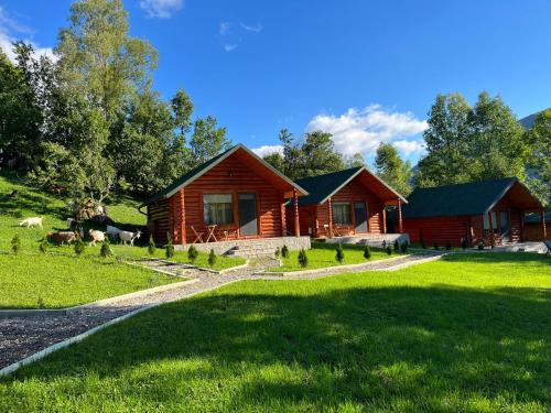 a log cabin with animals standing in front of it at Complex turistic Traisteni din Valea Doftanei in Podu lui Neag