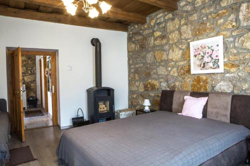 1 dormitorio con pared de piedra, cama y estufa de leña en Hegyaljai Panoráma Vendégház, en Szerencs