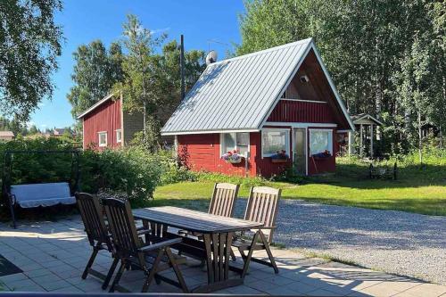 a wooden table and chairs in front of a red barn at Narikka Cottage, Cozy Stay in Central Kittilä, Near Levi Ski Resort in Kittilä