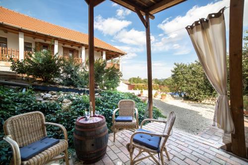 a patio with three chairs and a barrel at Hegyaljai Panoráma Vendégház in Szerencs