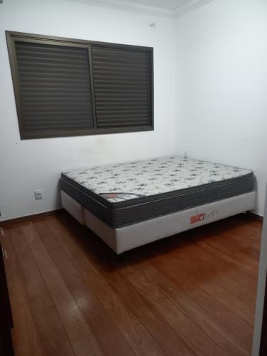 un lit est installé dans une pièce dotée de parquet. dans l'établissement Apt na região central , Completo com 2 camas casal, à Patos de Minas
