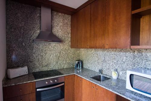 a kitchen with wooden cabinets and a sink and a stove at Sítio da Assumada in Lajes das Flores