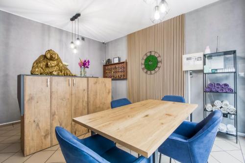 a dining room with a wooden table and blue chairs at Apartamenty Stara Praga - Wiatraczna in Warsaw