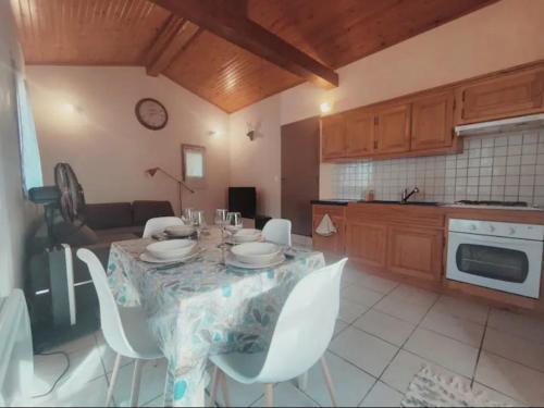 uma cozinha com uma mesa com cadeiras brancas e uma mesa em Auvillar: gîte au calme en pleine nature 2/4pers em Saint-Loup
