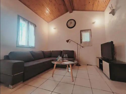 uma sala de estar com um sofá, uma mesa e um relógio em Auvillar: gîte au calme en pleine nature 2/4pers em Saint-Loup