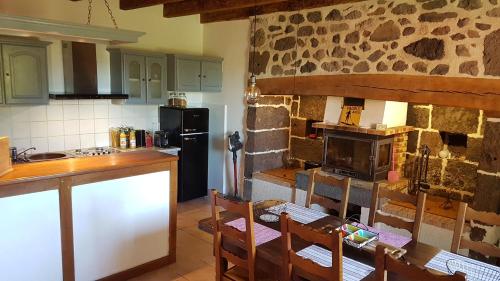 eine Küche mit einem Tisch und einer Steinmauer in der Unterkunft Résidence de Suzanne Gîte avec sauna privatif in Brommat