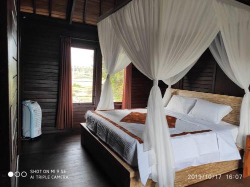 een slaapkamer met een hemelbed bij TEGESWOODHOUSE A with WiFi,Ac in Ubud