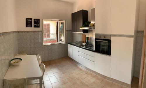 een keuken met witte kasten, een tafel, een tafel en een raam bij LALE Air conditioning, Wifi, Free parking HOME in Massa