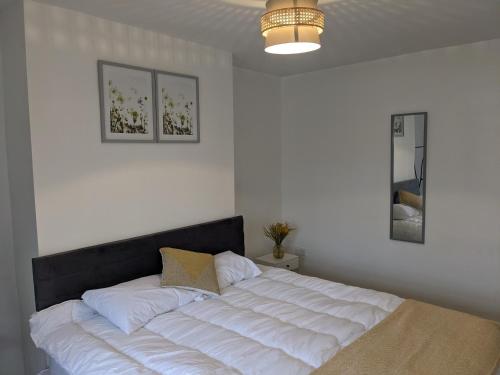 a bedroom with a large white bed with a black headboard at CityHost Apartments - Newcastle in Elswick