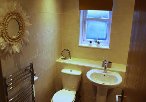 a bathroom with a toilet and a sink and a window at Cheery Craigie ground floor apartment in Perth