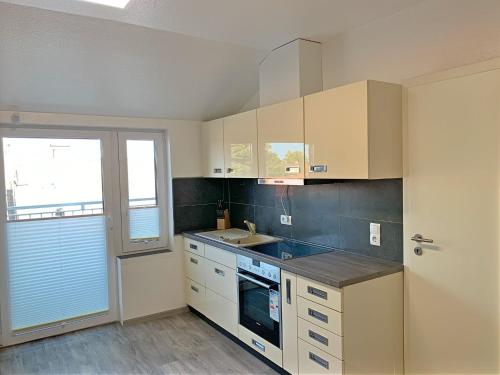 eine Küche mit weißen Schränken, einem Waschbecken und einem Fenster in der Unterkunft Galaxy Homestay in Emden