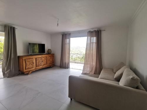 a living room with a couch and a television at Séjour en pleine nature, vue imprenable, jacuzzi in Contes