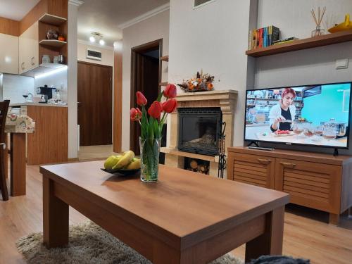 a living room with a vase of flowers and a television at Lusi Holiday, Смолянски езера in Smolyan