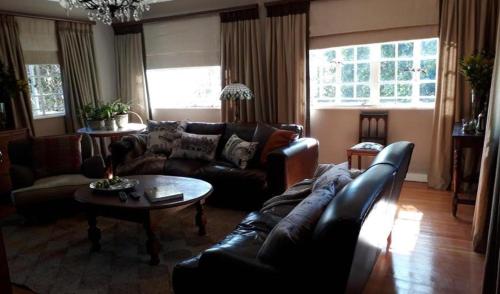 a living room with a leather couch and a table at The Great Gatsby Houghton in Johannesburg