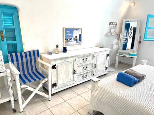 a bedroom with a dresser and a chair and a bed at Oia Sunset House Pothitou in Oia