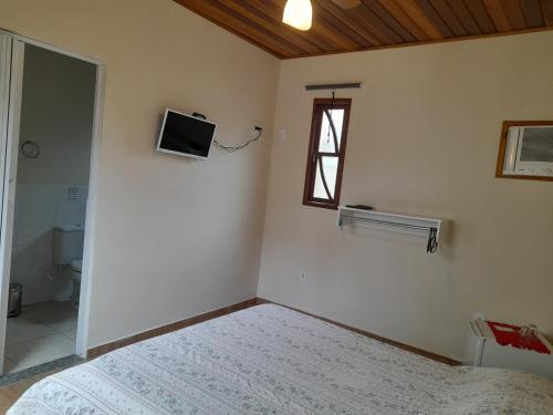 1 dormitorio con 1 cama y TV en la pared en Le Marchand de Sable- Guest House, en Búzios