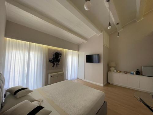 una camera bianca con letto e televisore di Off House Borgo Suite, Nettuno a Nettuno