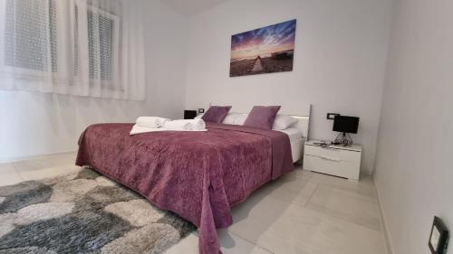 una camera da letto con un letto grande con una coperta viola di Holiday House Gavran a Vodice