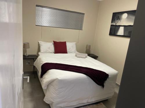 een slaapkamer met een groot bed met witte lakens en rode kussens bij Mall Of Africa Spot2 in Midrand