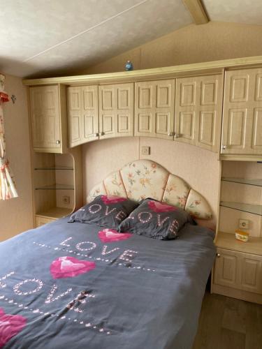 uma cama num pequeno quarto com armários brancos em Mobilhome em Noyelles-sur-Mer