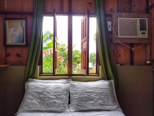 a bed in a room with a window and a bed sidx sidx sidx at Hospedaria Recanto da Paz in Itaporanga dʼAjuda