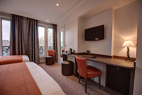 a hotel room with a bed and a desk with a television at Hôtel Du Midi Paris Montparnasse in Paris