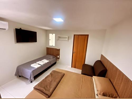 1 dormitorio con cama, sofá y TV en Pousada Avenida, en Teixeira de Freitas