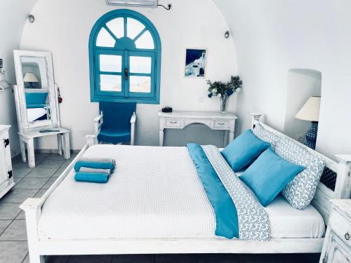 a bedroom with a white bed and blue pillows at Oia Sunset House Pothitou in Oia