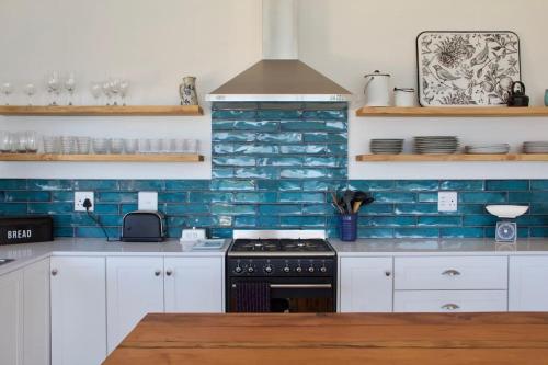 a kitchen with a stove and a blue brick wall at Seafront house with a view in Kleinmond
