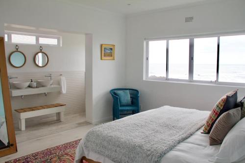 a bedroom with a bed and a bathroom with a sink at Seafront house with a view in Kleinmond