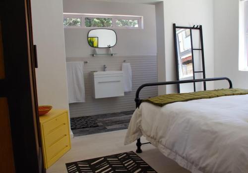 a bedroom with a bed and a sink and a mirror at Seafront house with a view in Kleinmond