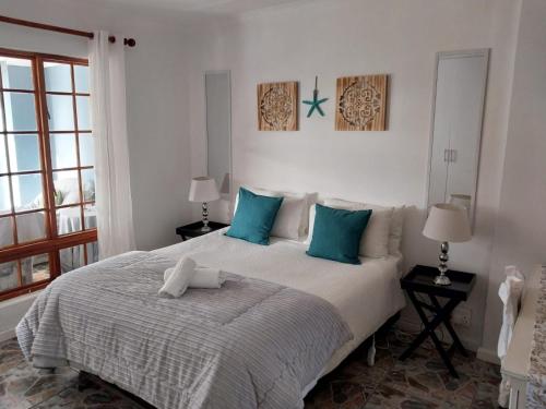 a bedroom with a large bed with blue pillows at GUINEA FOWL in Plettenberg Bay