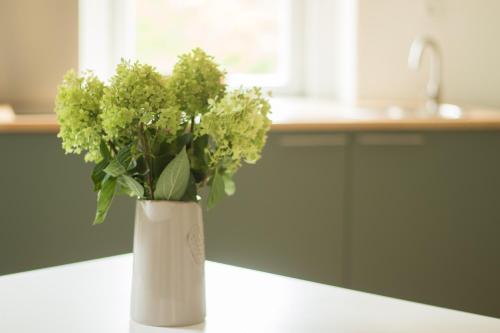 a white vase filled with green flowers on a counter at Ferienwohnung Schwalbennest in Kiebitz