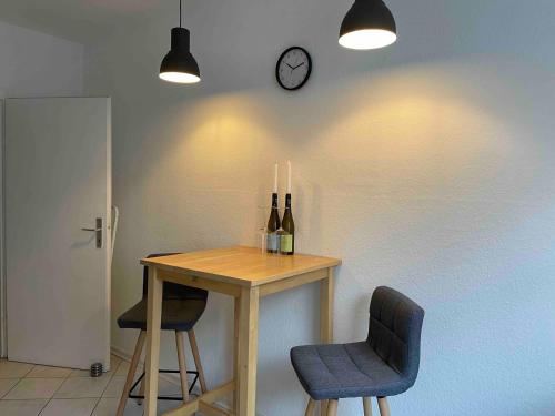 einem Tisch mit zwei Stühlen und einer Uhr an der Wand in der Unterkunft Apartment Strauss #EINS 1,5 Zi BS-östliches Ringgebiet in Braunschweig