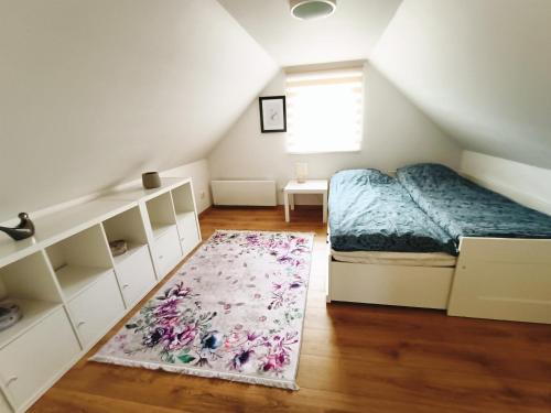 Schlafzimmer im Dachgeschoss mit einem Bett und einem Teppich in der Unterkunft Siedlisko Dwa Żurawie - Uroczy domek nad stawem, z kominkiem, obok konie 
