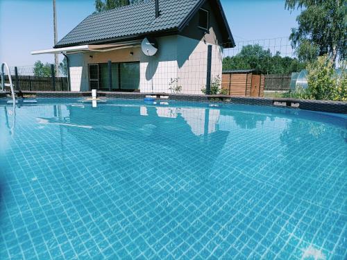 une grande piscine bleue en face d'une maison dans l'établissement Siedlisko Dwa Żurawie - Uroczy domek nad stawem, z kominkiem, obok konie, 