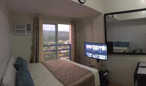 1 dormitorio con 1 cama, TV y ventana en Delta Charlie Staycation CDO, en Cagayan de Oro