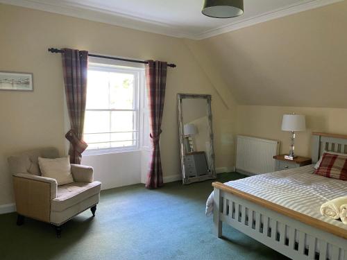 a bedroom with a bed and a chair and a window at Fabulous 2 Bedroom House just outside Edinburgh in Auchendinny