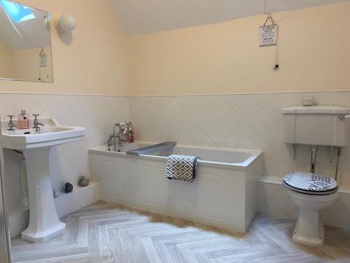 a bathroom with a tub and a sink and a toilet at Fabulous 2 Bedroom House just outside Edinburgh in Auchendinny