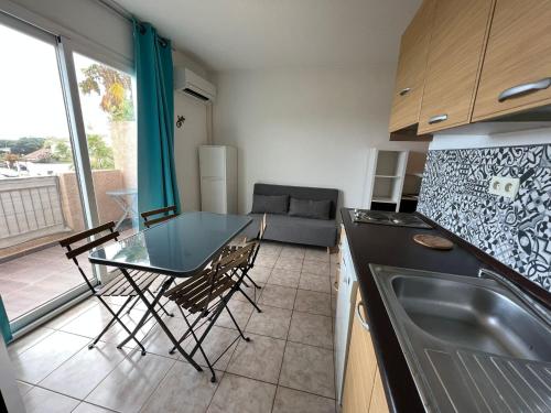 a kitchen with a table and chairs and a couch at Superbe appartement en résidence avec piscine proche plage in Linguizzetta